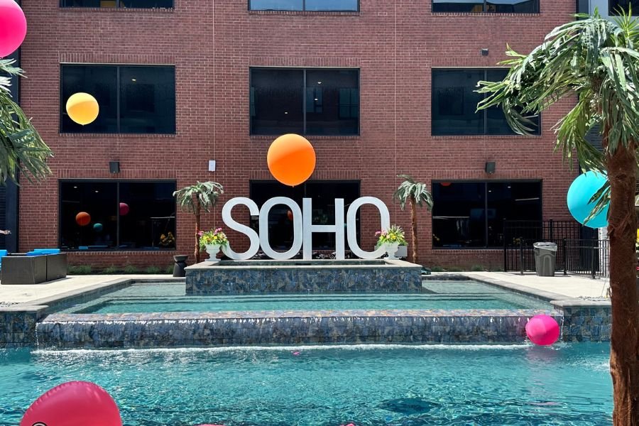 SoHo sign at the SoHo Pool with balloon and palm tree decor around,